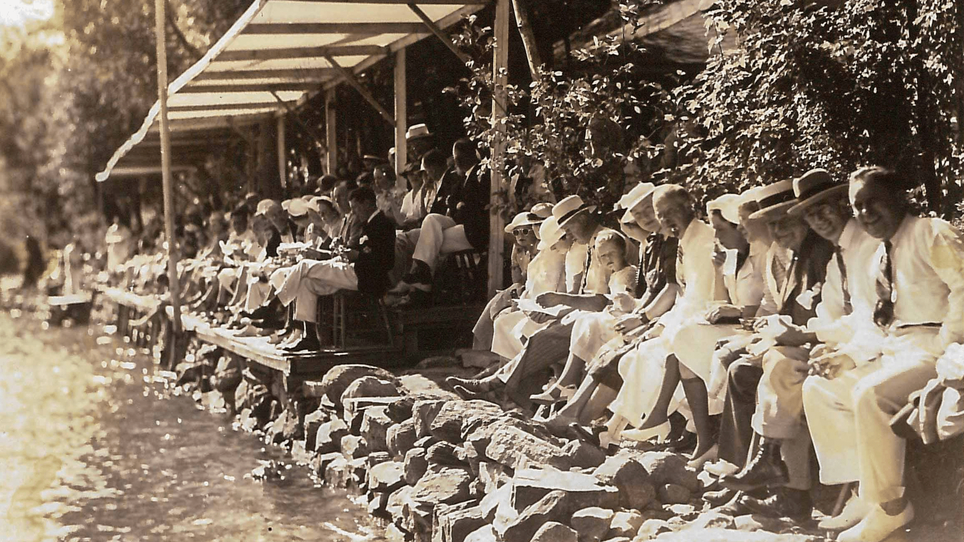 Sepia photo of people sitting on a rocky lake shore