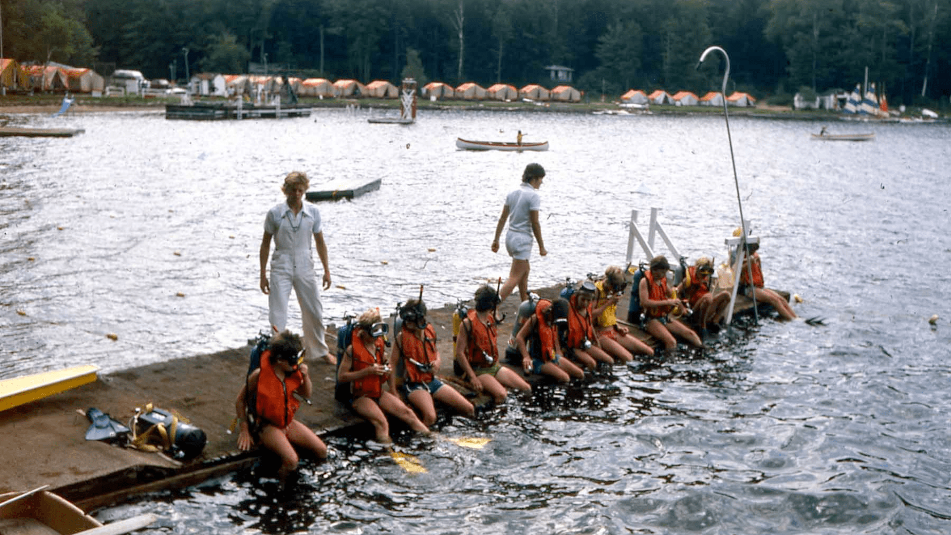 Children sitting on a dock wearing yellow swim flippers.