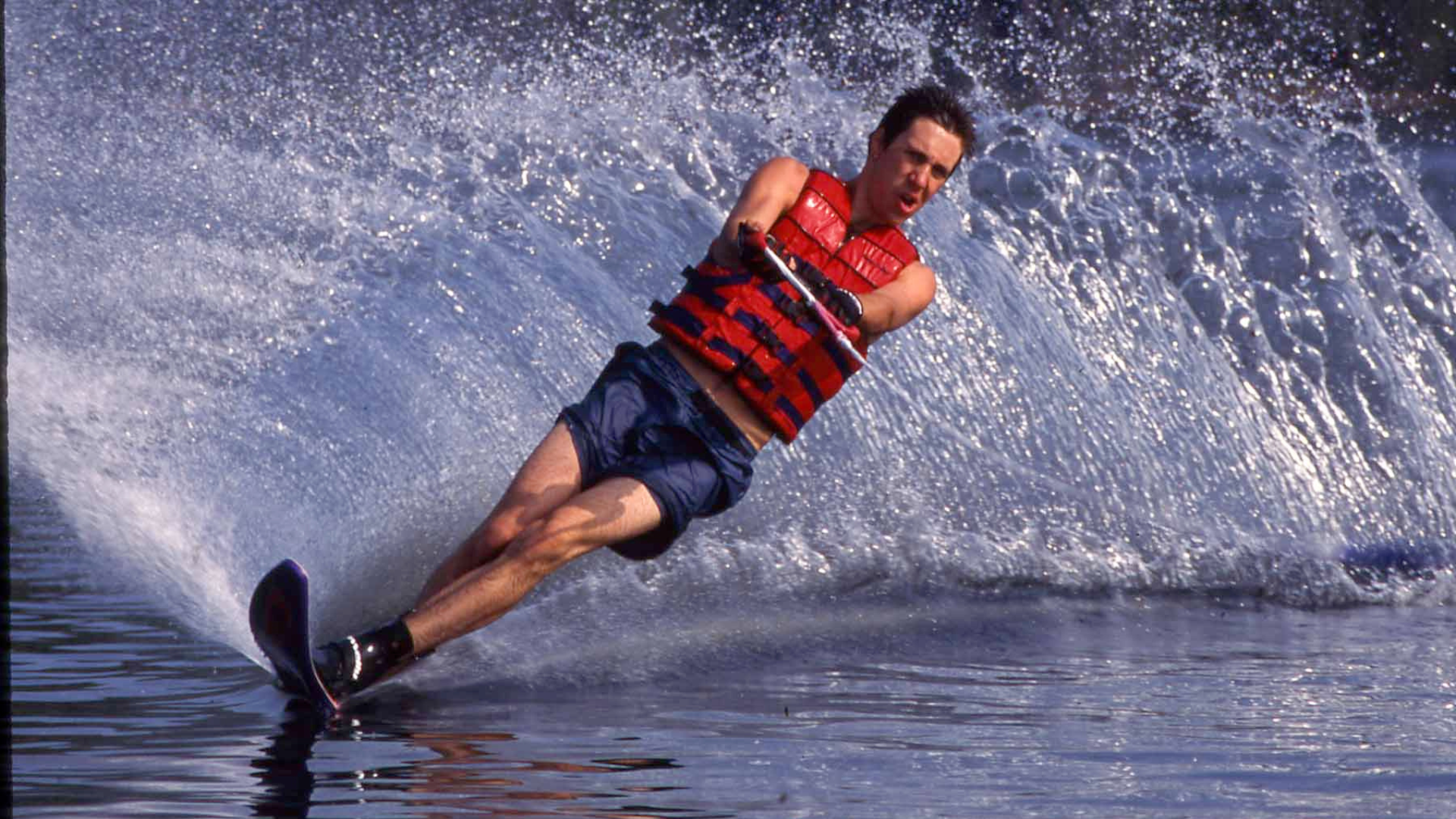 A man water skiing on a lake creating a splash.