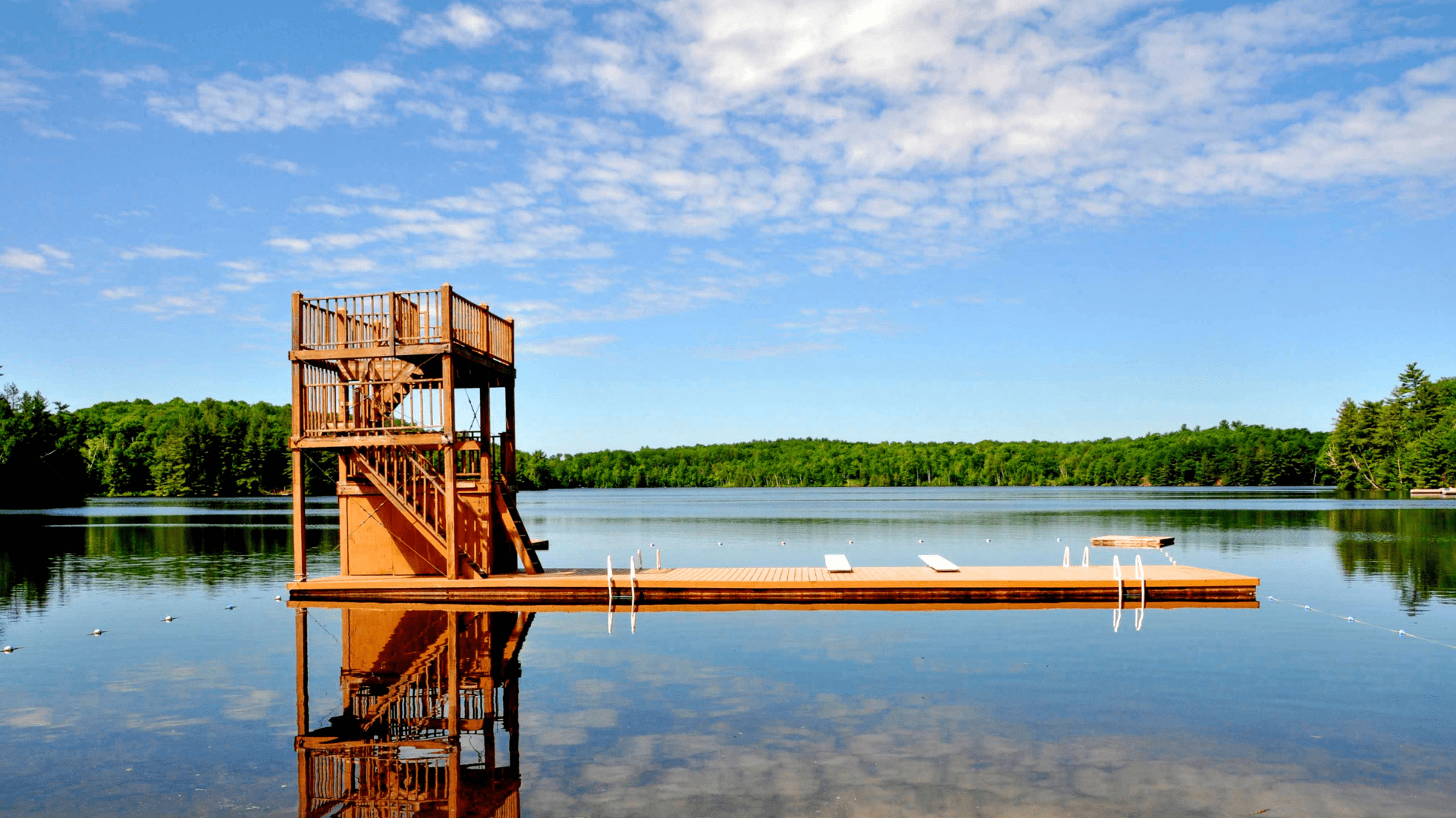 A wooden diving tower and dock on a calm lake.