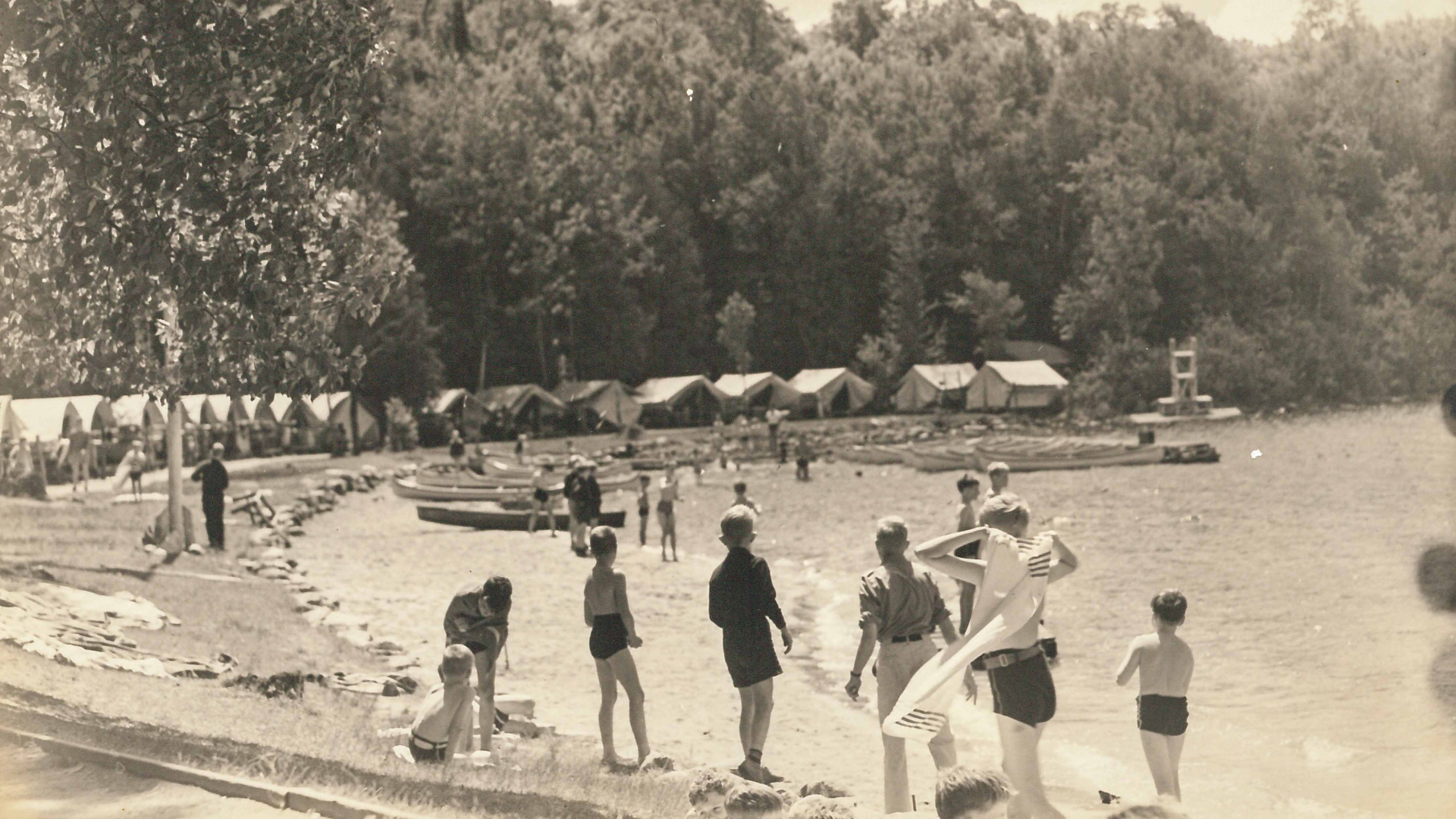 Vintage black and white photo of campers on the beach.