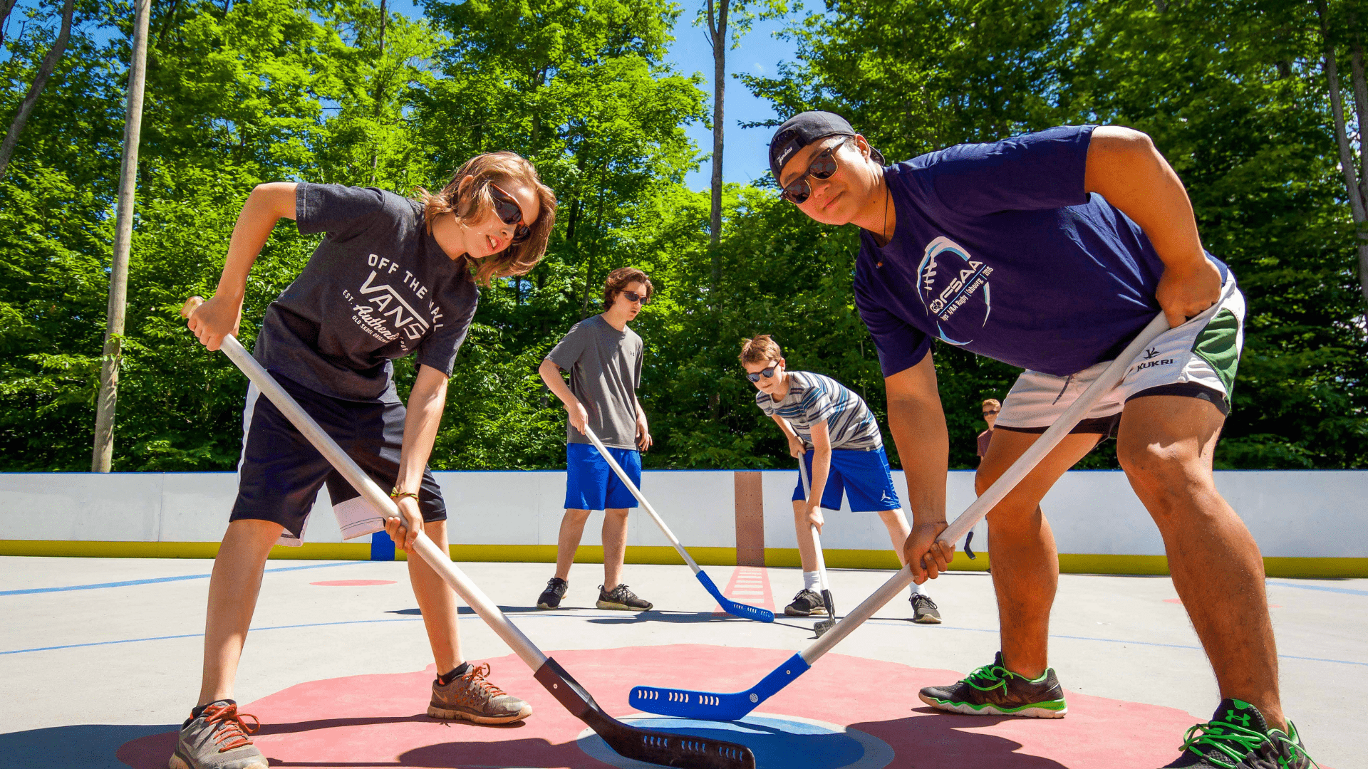 Campers playing a game of floor hockey on outdoor court.