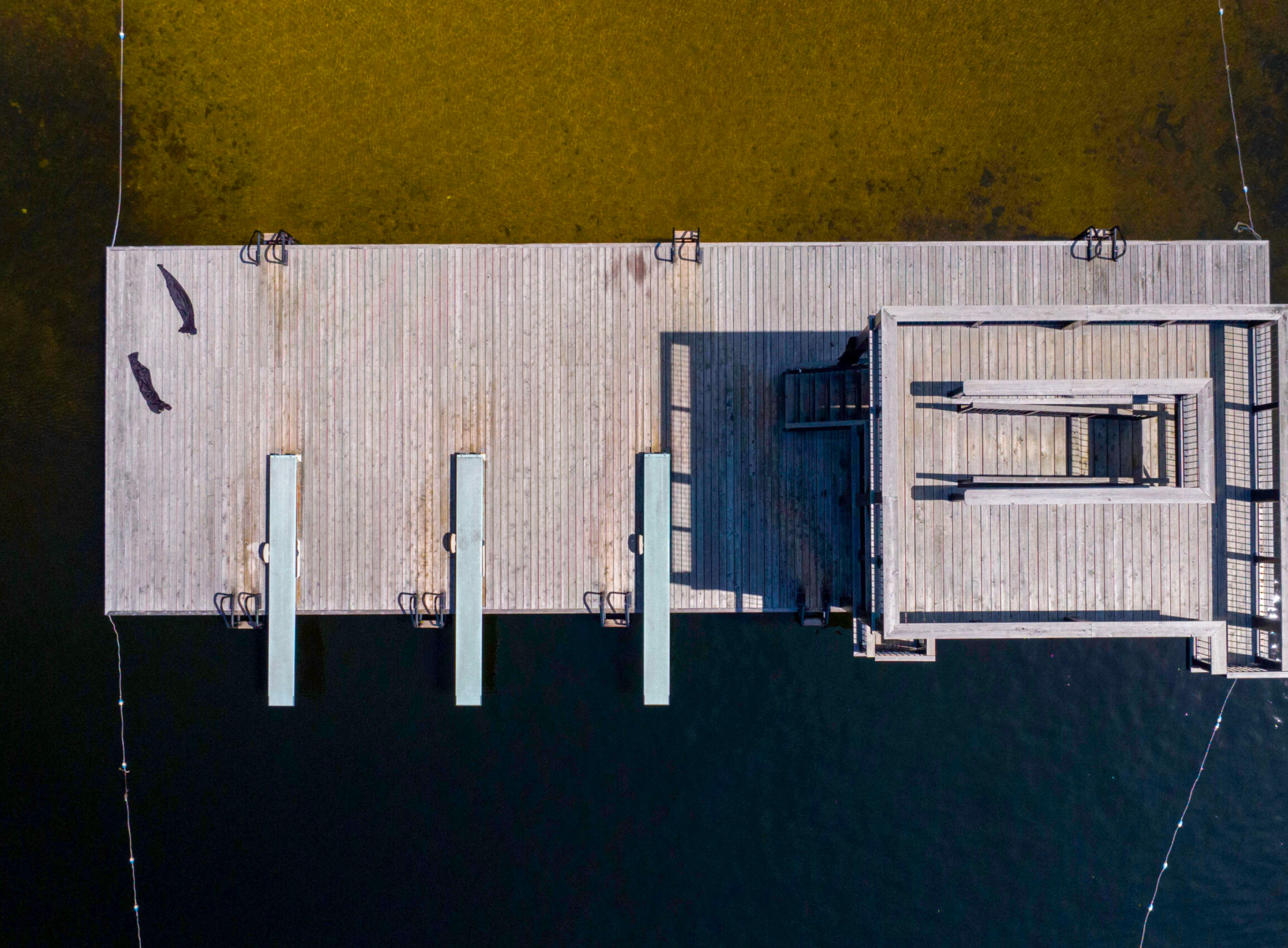 Bird's eye view of wooden docks extending over dark water.