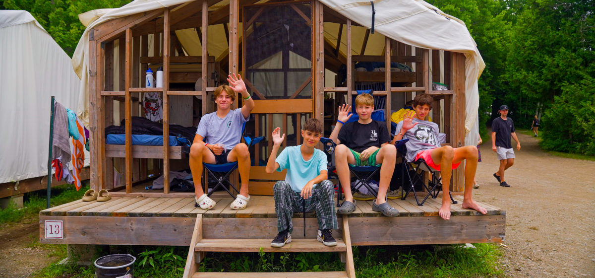 Campers sitting on steps of wooden cabin.