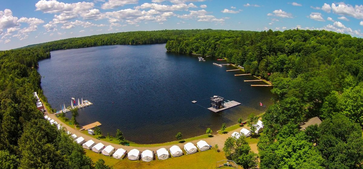 Aerial view of tents along lake shore.