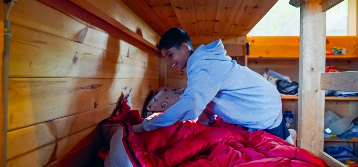 Camper arranging sleeping bag inside a cabin.