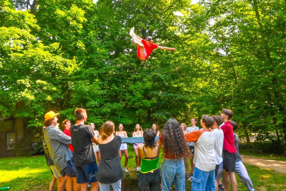 A group of campers tossing a person into the air.